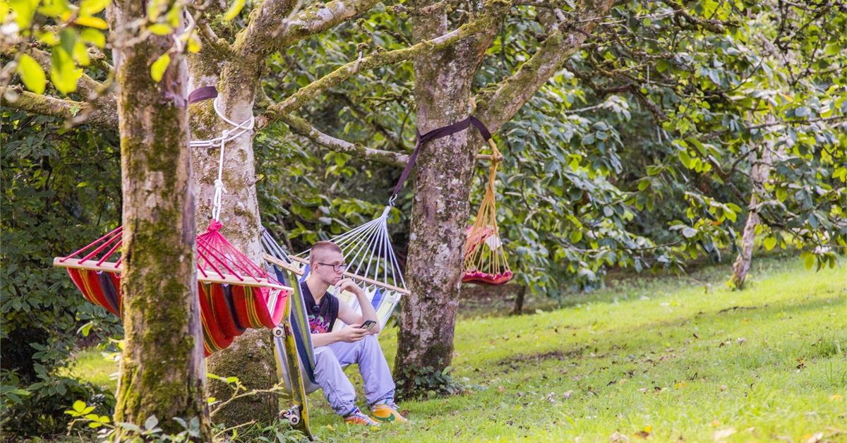 A student sitting at a hammock at Penryn Campus Walled Garden