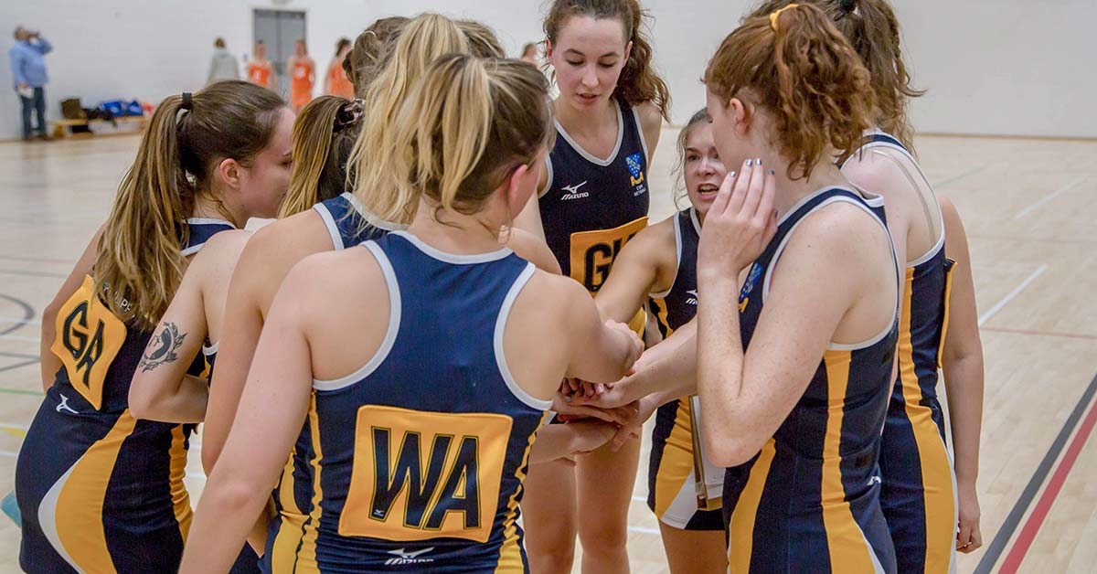 A group of netball players in a team huddle