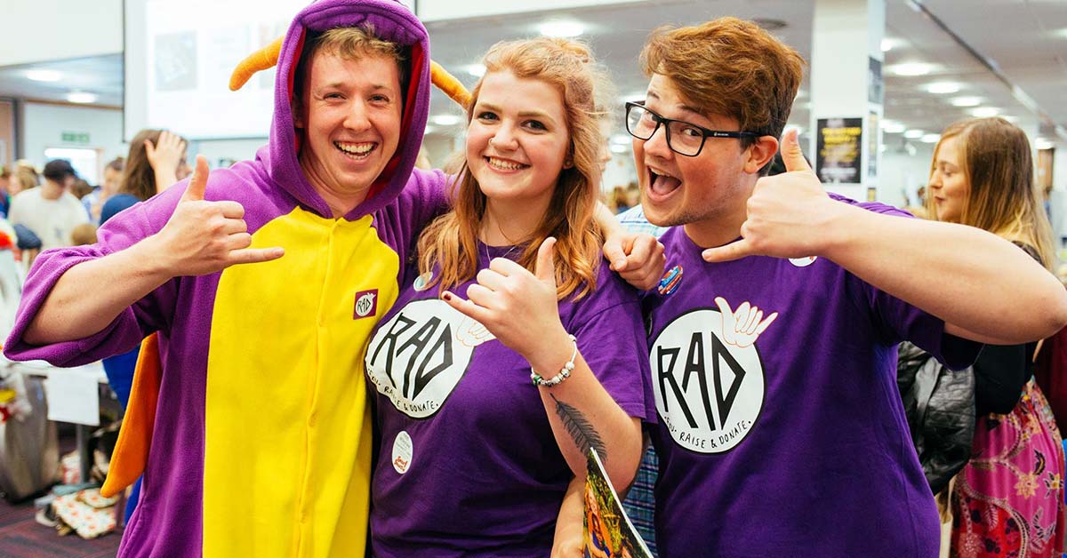 Three students smiling and doing a thumbs up at the camera