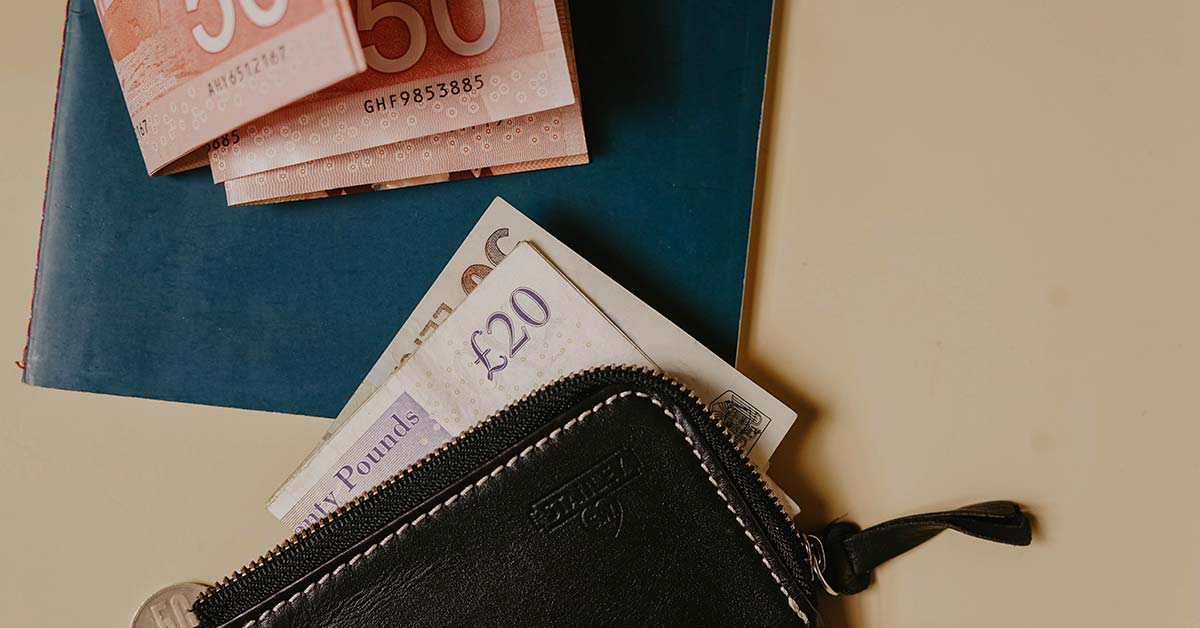 A wallet on a table with a £20 note sticking out