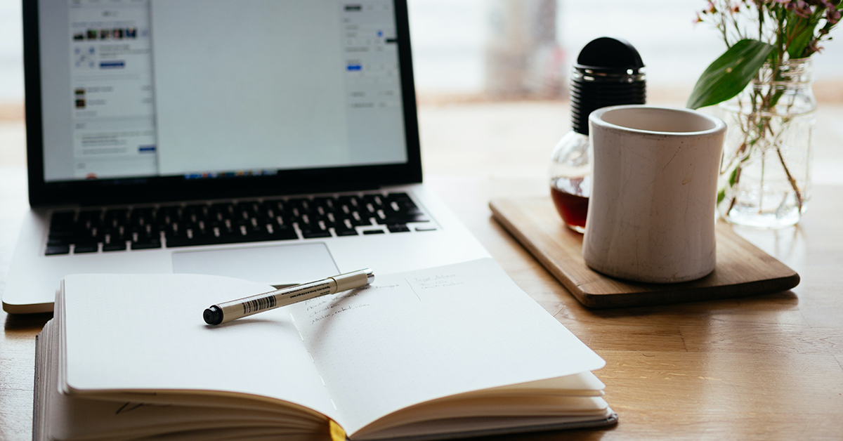 Photo of a laptop and notebook on a desk