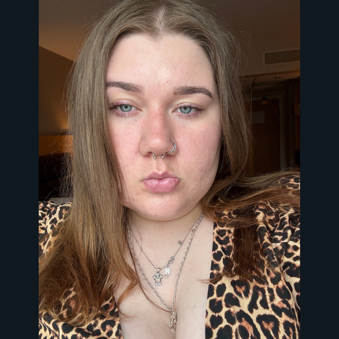 Bethan wears a leopard print top with a silver necklace and looks directly at the camera. She has brown hair, parted in the middle.