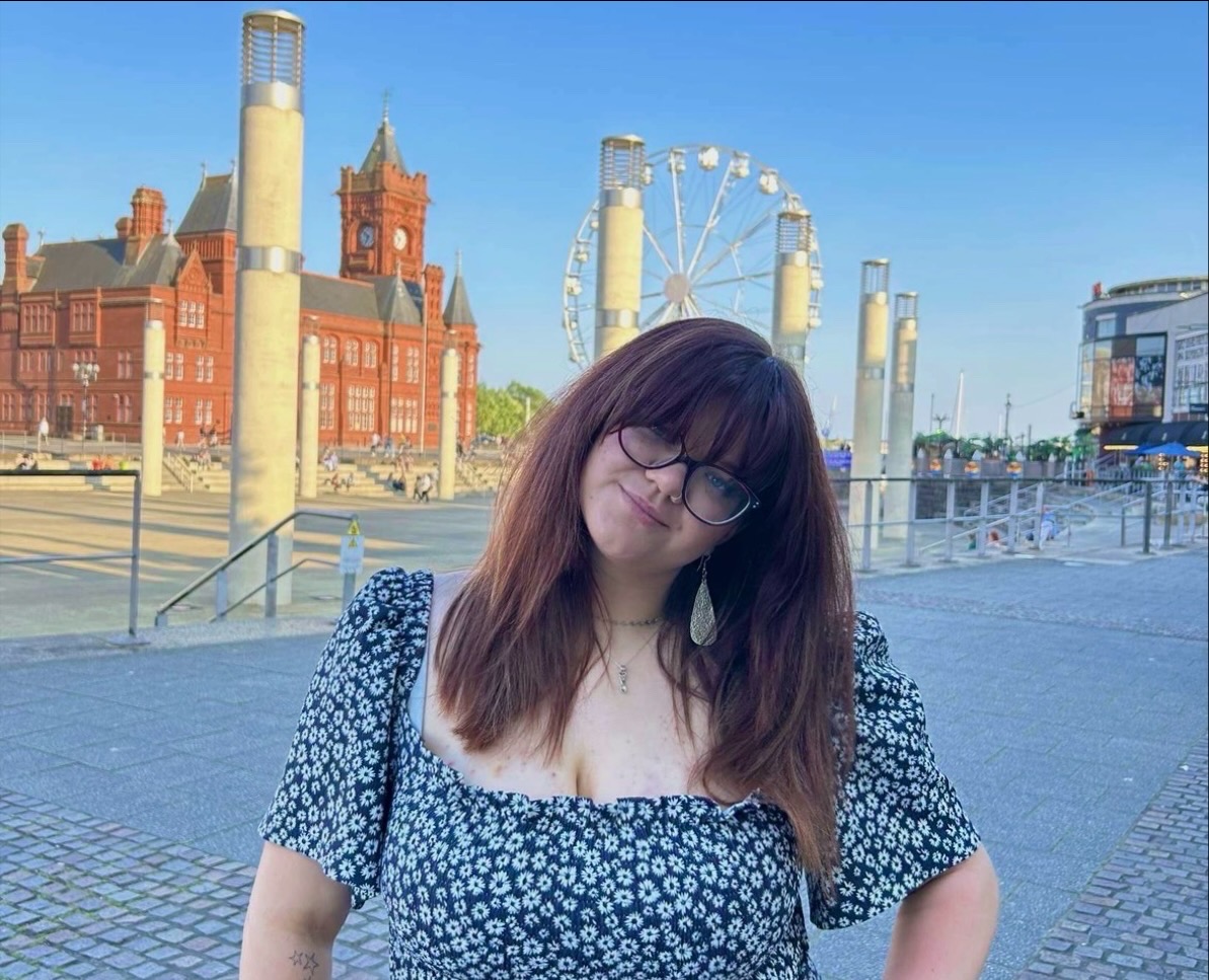 The image shows Niamh, a white woman stood outside with glasses on.