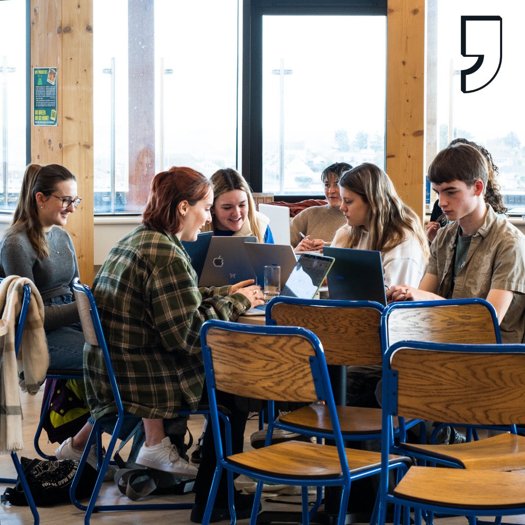 Students sat at a table in the Sustainability Cafe working on their laptops