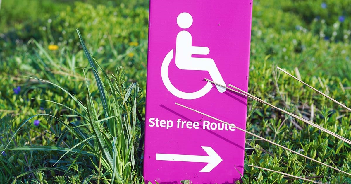 A pink step-free route sign with an arrow